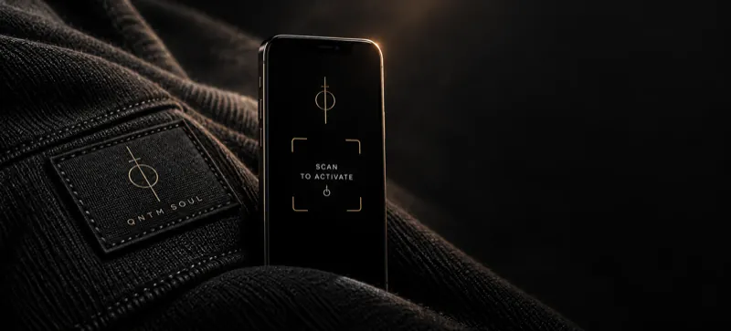 A QNTM SOUL woven label on dark fabric, beside a phone showing a scan frame reading “scan to activate”.